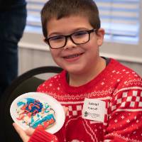 A kid showing off the cookie he decorated.